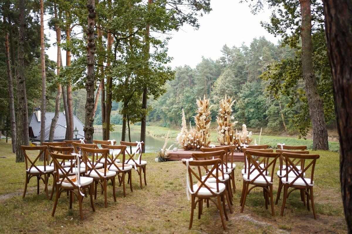 Ceremonia al aire libre con sillas de madera y arco floral